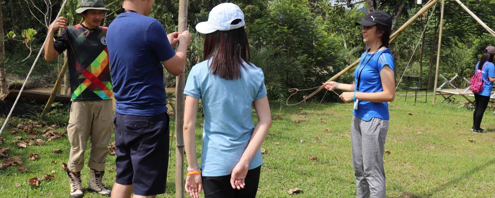 Youths learning how to tie camping knots at a leadership camp.